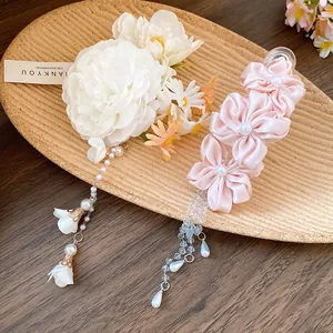 Detail showing pink and white fabric flower hair clips with elegant pearl tassels