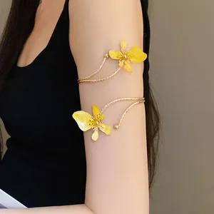 Bracelet de bras doré élégant avec détails de fleurs en émail jaune sur le bras d'une femme