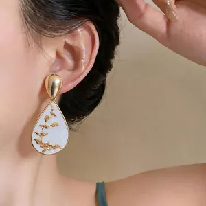 Close-up detail of retro New Chinese style teardrop earring with golden floral motif