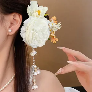 Detailed view of elegant white fabric flower hair clip with hanging pearl tassel accents.