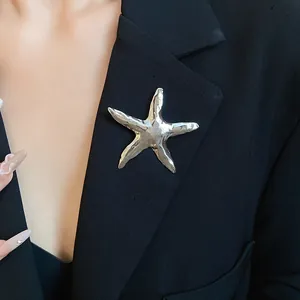 Detailansicht einer silberfarbenen Seestern-Brosche an einem schwarzen Blazer-Revers