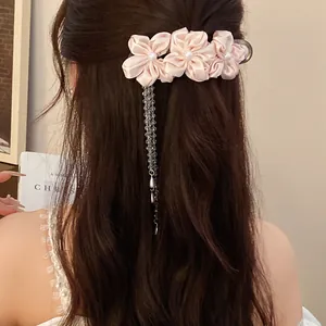 Detailed view of an elegant light pink fabric flower hair clip with pearl tassels