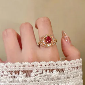 Dettaglio di un anello placcato oro 18K con gemma rossa e zirconi brillanti su dito