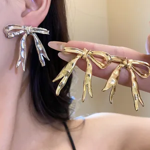 Close-up of elegant gold and silver bow-knot earrings with a polished smooth finish.