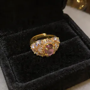Dettaglio ravvicinato di anello placcato oro 18K con pietra rosa e zirconi scintillanti