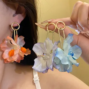 Detailed view of vibrant fabric flower earrings in peach, purple, and blue colors.