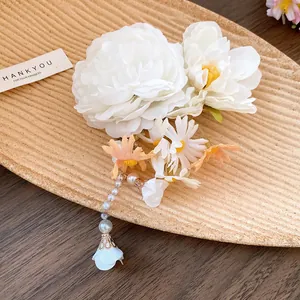 Detailed macro shot of a white floral hair clip with pearl tassel and daisy accents