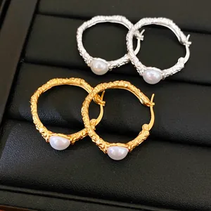 Macro view of wrinkled texture on silver and gold hoop earrings with white pearls