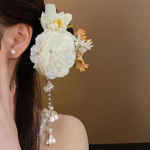 Close-up detail of white fabric flower hair clip featuring elegant long pearl tassels