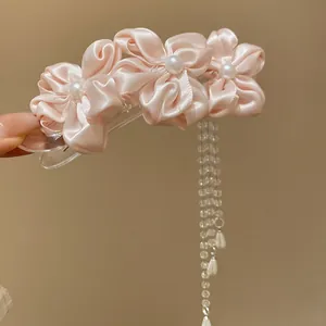 Detailed shot of a pink satin floral hair clip with elegant pearl tassels
