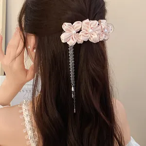 Close-up of pink fabric flower hair clip with pearl center and dangling bead tassels