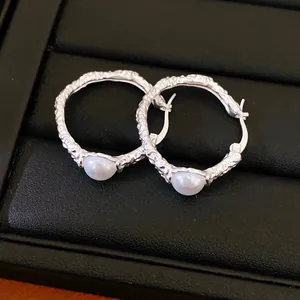 Detail showing texture of silver wrinkled hoop earrings with elegant white pearl.