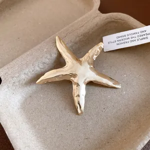 Nahaufnahme einer strukturierten Vintage-Gold-Seestern-Brosche vor neutralem Hintergrund