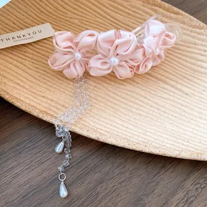 Close-up of pink fabric flower hair clip with elegant pearl and crystal tassels.