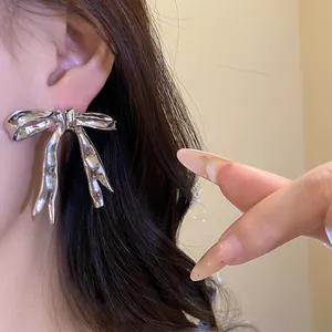 Close-up of vintage silver bow earrings worn on an ear for a stylish look.