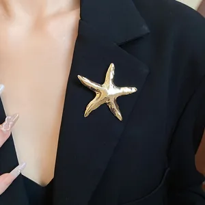 Detailansicht einer goldenen Seestern-Brosche mit Vintage-Faltenoptik an einem schwarzen Revers