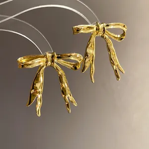 Macro view of vintage gold ribbon bow earrings featuring a glossy metallic finish