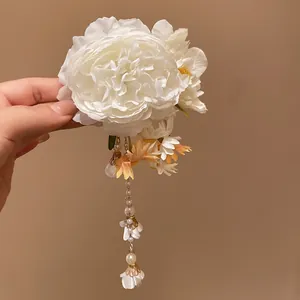 Detailed view of elegant white fabric flower hair clip with dangling pearl tassels.