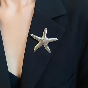 Detailansicht einer silbernen Seestern-Brosche auf einem schwarzen Blazer-Revers