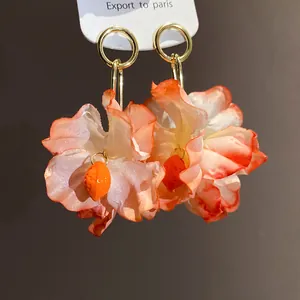 Close-up of elegant fabric flower earrings with orange gradient petals and lemon charms