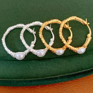 Close-up of elegant gold and silver textured hoop earrings featuring dainty white pearls