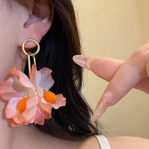 Close-up detail of a large peach fabric flower drop earring worn on an Asian model's ear.