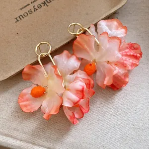Detailed macro shot of fabric flower earrings with soft orange and white gradient petals.