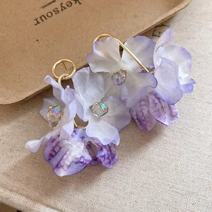 Close-up of delicate purple fabric flower earrings with iridescent crystal beads