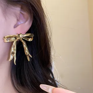 Detailed close-up showing texture of vintage gold glossy bow stud earrings worn on ear