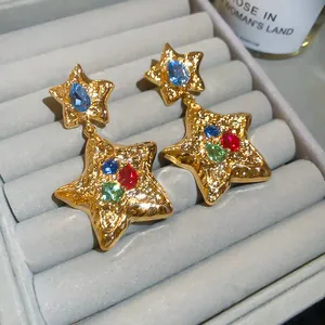 Vintage gold pleated star earrings with colorful rhinestone insets in a jewelry tray