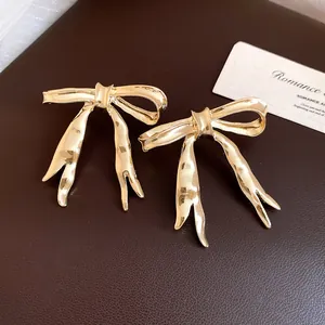 Detailed close-up view of vintage gold bow earrings with a textured metal finish