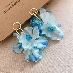 Macro detail view of blue fabric flower earrings with crystal accents and gold hoop