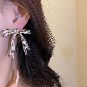 Detail showing silver bow-knot stud earring with high-polish metallic finish