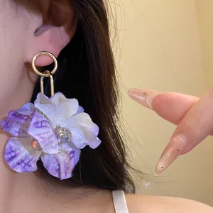 Close-up of purple fabric flower earring with crystal center on a model.