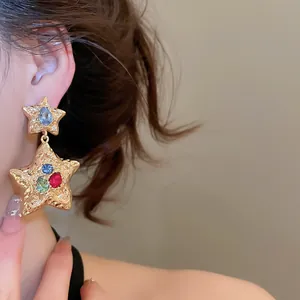 Stunning gold-tone star drop earrings accented with colorful gemstones detail view