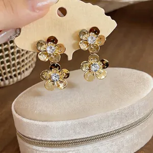 Elegant French style golden metal flower earrings with zircon center on display card