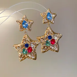 Detailed macro view of gold wrinkled star earrings with vibrant colorful rhinestones
