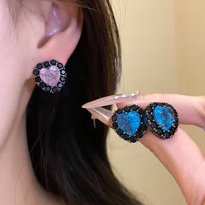 Close-up of elegant heart-shaped zircon earrings with black rhinestones and silver needles.