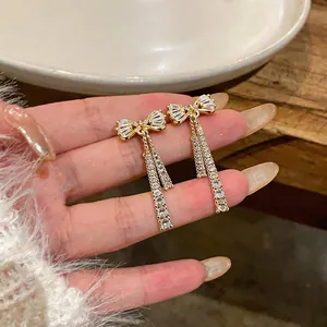 Détail macro de boucles d'oreilles nœud plaquées or 14 carats avec chaînes en zircone