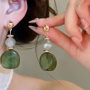 Pendientes de resina con cuentas jaspeadas verdes y un diseño geométrico dorado