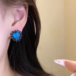 Close-up view of an elegant blue heart zircon stud earring with a black stone halo setting