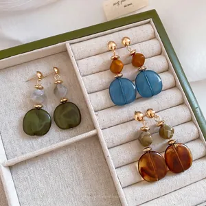 Elegantes pendientes vintage de resina jaspeada en un joyero, diseño geométrico