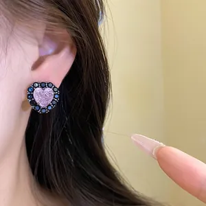 Close-up detail of a pink glitter heart stud earring with black zircon border on a model's ear