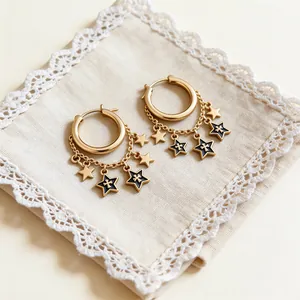 Detailed view of gold hoop earrings with black enamel star charms and delicate chains