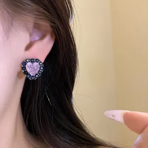 Close-up view of a pink heart-shaped zircon stud earring with a black stone border on ear