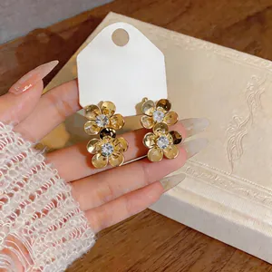 Detailed macro shot of gold-plated flower stud earrings featuring sparkling zircon centers