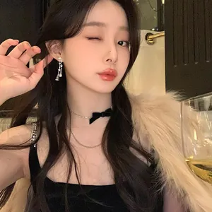 Detailed view of elegant zircon heart ear clip with teardrop tassels on an Asian model.