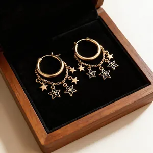 Close-up of gold hoop earrings with star charms and black enamel cross pendants