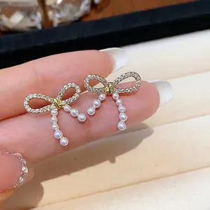 14K gold plated bow stud earrings with micro-pave crystals and dangling pearls