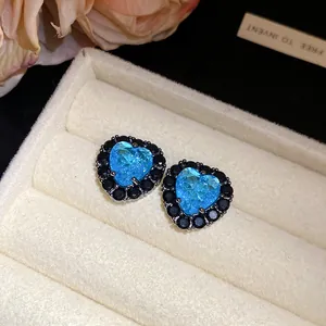 Close-up of heart-shaped blue zircon stud earrings with black stone halo in a gift box.